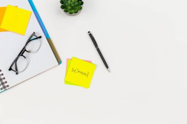 Not defteri, gözlük, kalem ve kağıt anımsatıcıları beyaz arkaplan, üst görünüm, kopya alanı, okul konsepti.