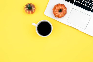 Laptop, kahve ve balkabağı sarı arka planda, üst manzara, ofis işi, kopyalama alanı.