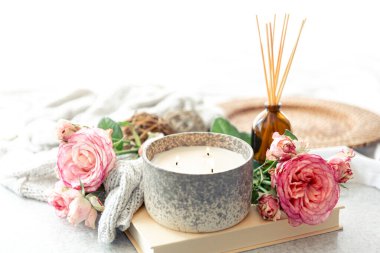 Aroma yağı yayıcı lamba, pembe çiçekler ve bulanık arkaplanda mum içeren spa kompozisyonu.