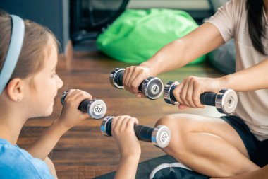 Kızıyla spor yapan bir kadın spor salonunda yerde, anne ve bebek birlikte antrenman yapmaktan mutluluk duyar..