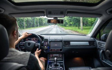 Bir erkek sürücü şehrin sokaklarında araba kullanıyor, arabanın içinden bir manzara..