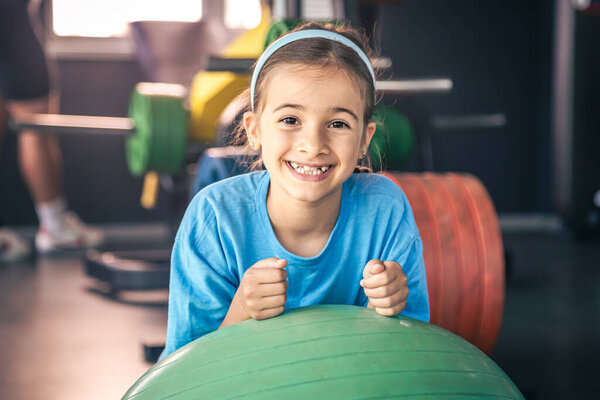 Happy girl stretches her body on a fitball in the gym, gymnastics and pilates for children.