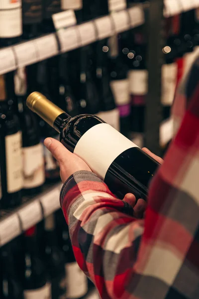 Mężczyzna Trzymający Butelkę Wina Monopolowym Sklepie Winem Wybierający Właściwe Wino — Zdjęcie stockowe