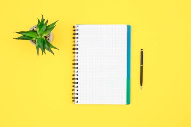 Sarı arkaplan üzerindeki defter ve kalem izole, üst görünüm, kopyalama alanı.