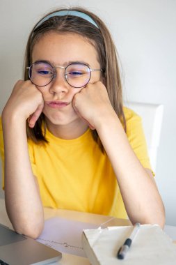 Sıkıcı öğrenci ödevlerini yaparken dizüstü bilgisayar kullanmaktan sıkılmış, üzgün genç kız sınav için hazırlanıyor..
