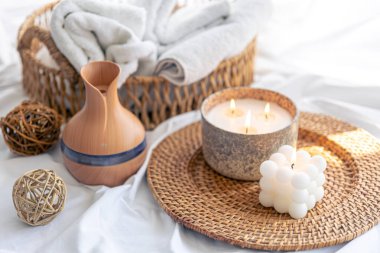 Aroma yayıcılı spa kompozisyonu, bulanık arkaplanda havlular ve mumlar..