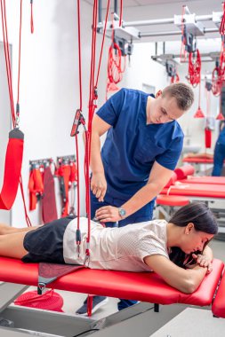 Fizyoterapist, özel bir askıya alma halat sistemi üzerinde rehabilitasyon gören modern bir fitness merkezinde kadın hastaya yardım ediyor..