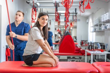 Genç bir kadın spor salonunda kişisel antrenörle çalışıyor. Modern rehabilitasyon fizyoterapi erkek çalışanı ve müşterisi..