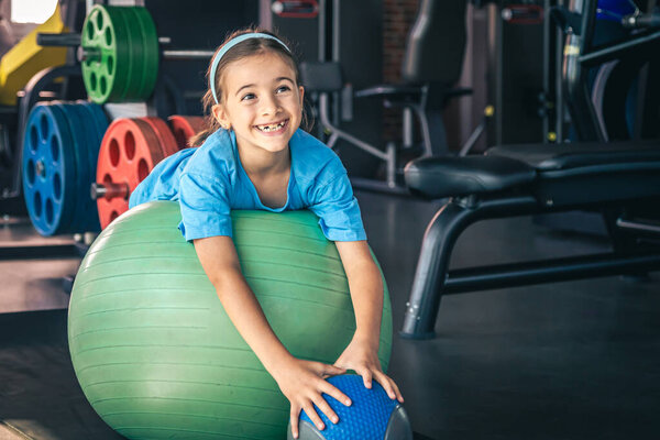 Happy girl stretches her body on a fitball in the gym, gymnastics and pilates for children.