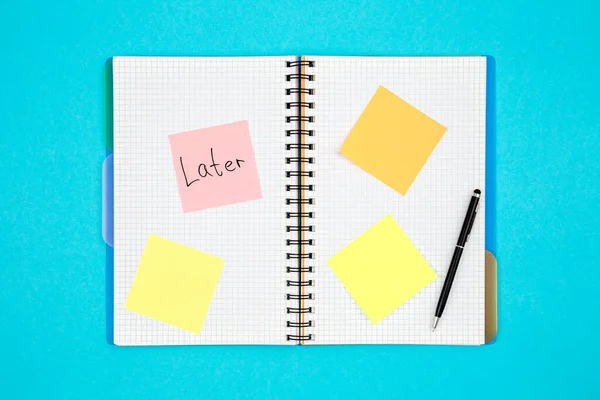 Notepad with paper reminders and written word Late on a blue background, top view.