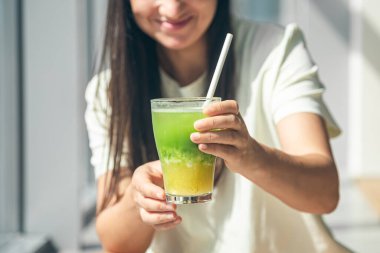 Sıcak, güneşli bir günde, bir kadının elinde serin yeşil ve sarı yaz içeceği..