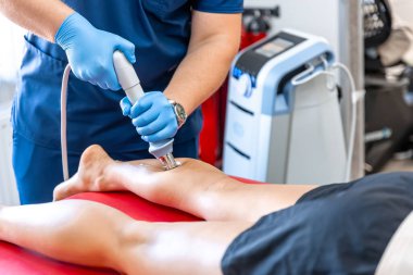 Şok dalgası terapisi, manyetik alan, rehabilitasyon, fizyoterapist doktor bir hastanın bacağını ameliyat eder..