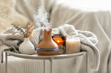 Aroma kompozisyonu, modern aroma yağı yayıcısı, mumlar ve odanın içinde örülmüş bir element..