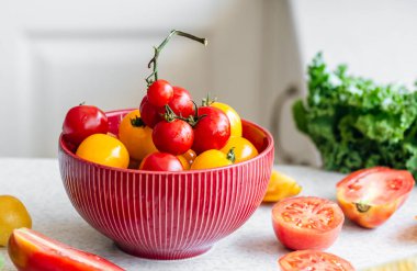 Yakın plan, mutfak masasında bir kase olgun kırmızı ve sarı domates, hasat ve sağlıklı beslenme konsepti.