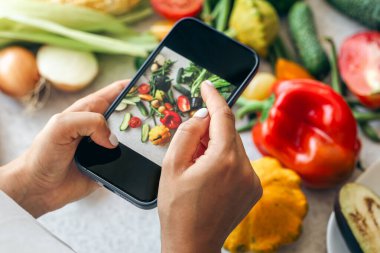Kadın elleri sebzelerin akıllı telefon fotoğrafları, sosyal medya için telefon fotoğrafçılığı veya blog yazarlığı, sağlıklı beslenme.