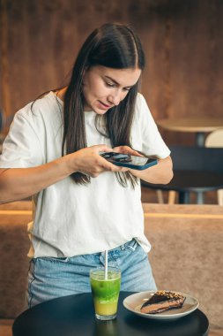 Çekici genç bir kadın kahvaltını evde yapıyor, fotoğraf çekiyor, blog yazıyor..