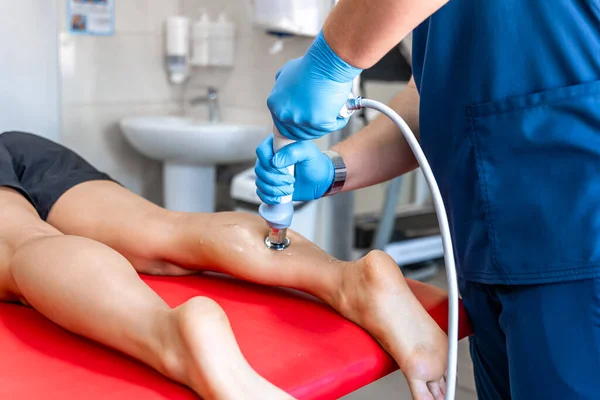 Shock wave therapy, the magnetic field, rehabilitation, physiotherapist doctor performs surgery on a patients shin.