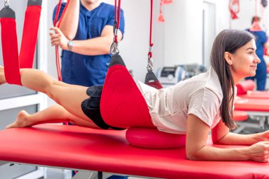 Genç bir kadın spor salonunda kişisel antrenörle çalışıyor. Modern rehabilitasyon fizyoterapi erkek çalışanı ve müşterisi..