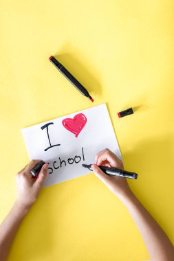 Okulu seviyorum. Çocukların el yazısı sarı arka plan üzerine bir makale yazıyor..