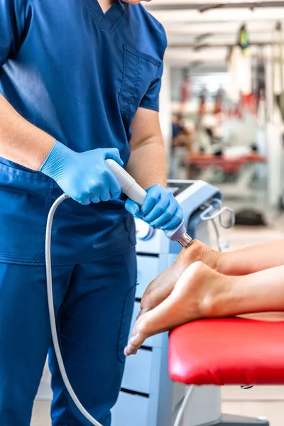 Shock wave therapy, the magnetic field, rehabilitation, physiotherapist doctor performs surgery on a patients heel.