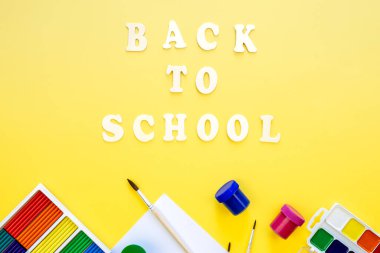 Renkli okul gereçleri ve sarı arka planda ahşap harfler. Okul konseptine geri dönüyoruz..