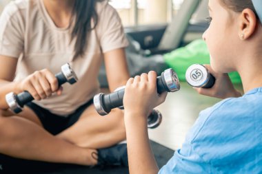 Kızıyla spor yapan bir kadın spor salonunda yerde, anne ve bebek birlikte antrenman yapmaktan mutluluk duyar..