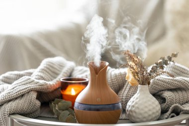 Aroma kompozisyonu, modern aroma yağı yayıcısı, mumlar ve odanın içinde örülmüş bir element..