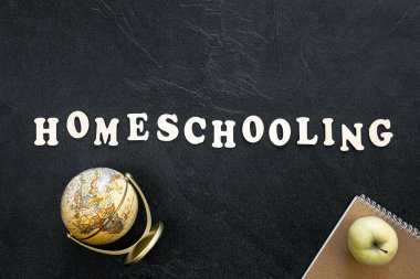 Tasarımınız için koyu dokulu tahtadaki ahşap harflerden oluşan ev eğitimi kelimesi, üst görünüm.