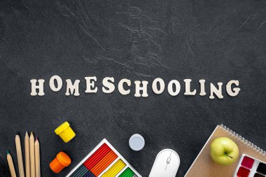 Ahşap harflerden, renkli okul malzemelerinden ve tasarım için koyu dokulu bir tahtaya yapıştırılmış kırtasiyelerden oluşan ev yapımı bir kelime..