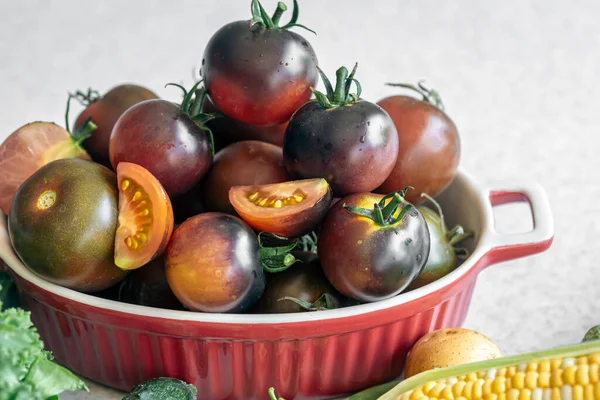 Close-up, a bowl of ripe black tomatoes on the kitchen table, the concept of harvest and healthy eating.