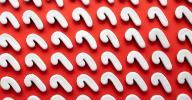 Kırmızı arka planda bir sürü zencefilli şeker kamışlı kurabiye var..