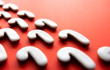 Kırmızı arka planda bir sürü zencefilli şeker kamışlı kurabiye var..