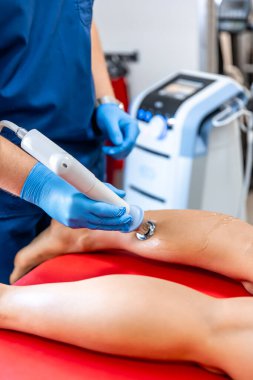 Şok dalgası terapisi, manyetik alan, rehabilitasyon, fizyoterapist doktor bir hastanın bacağını ameliyat eder..