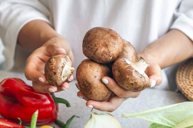 Mutfaktaki bir kadının elinde çiğ mantar mantarı..