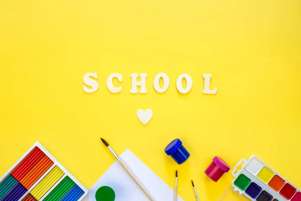 黄色の背景にカラフルな学校用品や木製の手紙 学校のコンセプト トップビューに戻る — ストック写真