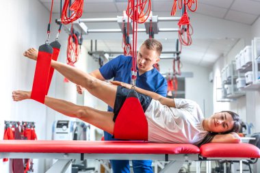 Genç bir kadın spor salonunda kişisel antrenörle çalışıyor. Modern rehabilitasyon fizyoterapi erkek çalışanı ve müşterisi..