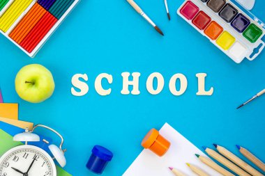 Renkli okul malzemeleri ve mavi arka planda ahşap harfler, okul konseptine geri dönüş, üst manzara..