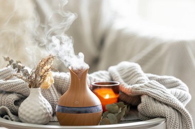 Aroma kompozisyonu, modern aroma yağı yayıcısı, mumlar ve odanın içinde örülmüş bir element..