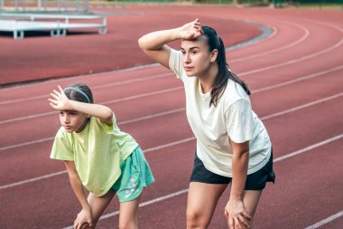 Antrenmandan sonra anne-kız stadyumda yorulmuş bir şekilde annesi ile birlikte formda kalıyor..