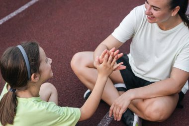 Stadyumda güçlü bir anne-kız beşlik çakıyor. Kız, annesini formda tutarak destekliyor..
