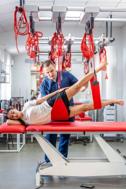 Rehabilitasyon merkezinde askıya alınan kadın hasta, tedavi egzersizleri ve kırmızı kordon saplarında nöromüsküler aktivasyon, nöro-aktifleştirme..
