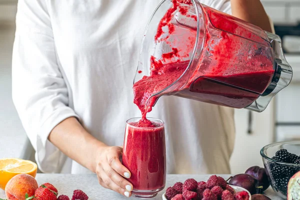 自宅でデトックススムージーを作る女性 ガラスに赤いスムージーを注ぐ女性 健康的な食品コンセプト — ストック写真