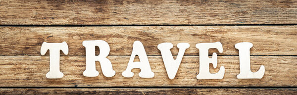 The word Travel written on wood letters, text on wooden table for your design, top view concept.