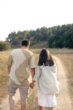 Bir adam ve bir kadın, el ele tutuşmuş, mutlu bir aile, birbirine aşık bir çift, arkadan bakıyorlar..