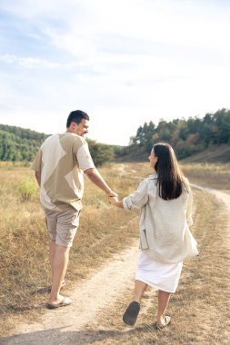 Bir adam ve bir kadın, el ele tutuşmuş, mutlu bir aile, birbirine aşık bir çift, arkadan bakıyorlar..