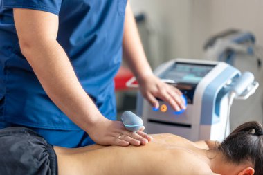 Doktor bir hastanın sırtını tedavi etmek için makine kullanıyor, T-CaRe teknolojisi, Resistive ve Kapasite Terapisi.
