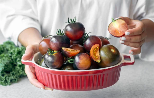 Close-up, a bowl of ripe black tomatoes on the kitchen table, the concept of harvest and healthy eating.
