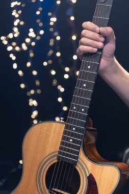 Gitaristin elinde akustik gitar, arka planda Bokeh, müzikal arka planda Noel konsepti..