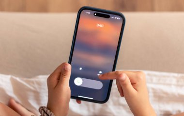 Bulanık bir arkaplanda baba çağrısının görüntülendiği telefonu tutan çocuk ellerini kapat.