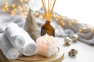 Havlu, mum ve tütsü içeren bir Noel spa kompozisyonu bulanık bir zemin üzerinde bokeh ışıkları ile yapışıyor..
